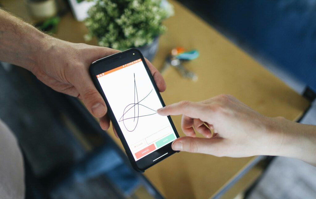 Two people completing a digital transaction with electronic signature on a smartphone screen.